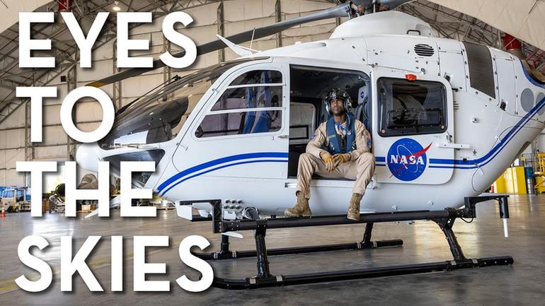 Shannon Gregory in uniform sitting in nasa helicopter with words "eyes to the skies" overlaid