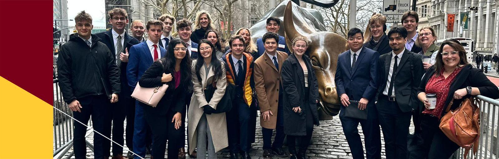Students gather around the iconic bull statue on Wall Street.