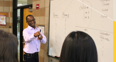 Professor Ibrahim Keita points at a student, smiling.
