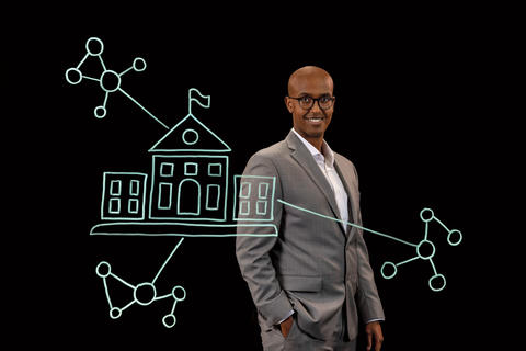 Abdifatah Ali stands behind an illustration of a university and networks.