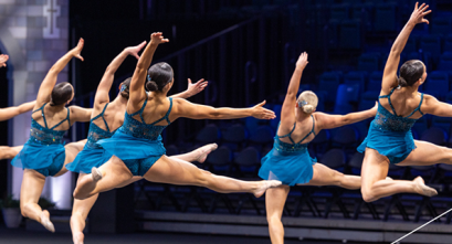 The University of Minnesota Dance Team turning in sync mid-air during competition routine.