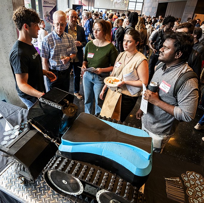 A student provides an elevator pitch while standing next to his snow-clearing robot.