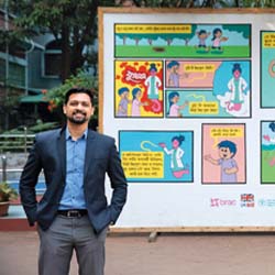 Monzur Morshed Patwary poses in front of COVID-19 PSA comic