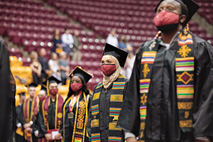 Class of 2021 graduates standing at their commencement ceremony at Mariucci Arena.
