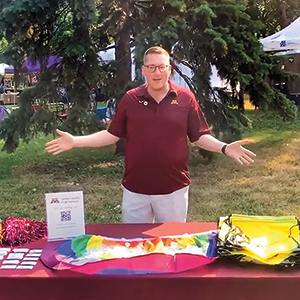 Alum, KC Glaser, smiles in front of the Carlson School's Pride table at the Twin Cities Pride Festival in July 2021.