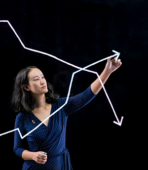 Associate Professor of Accounting Vivian Fang in front of black screen drawing with a light pen