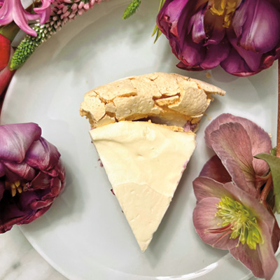 A slice of pie on a plate with pink flowers decoratively arranged around it