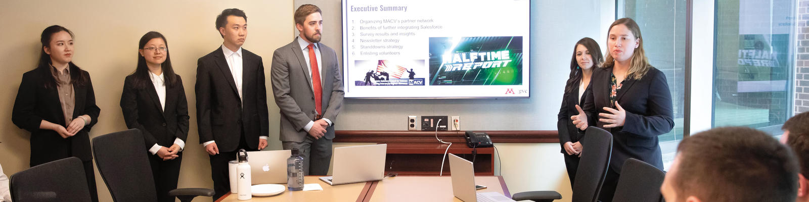 A group of graduate students gives a presentation in a board room.