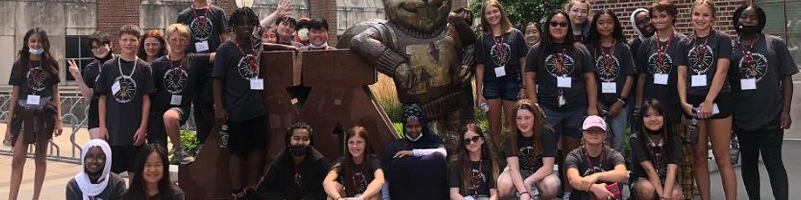 Group of students posing with gold statue of Goldy Gopher