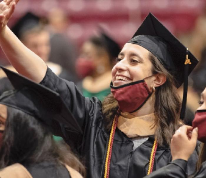 Two 2021 MBA graduates wave to friends and family at their 2021 Commencement ceremony at Mariucci Arena.