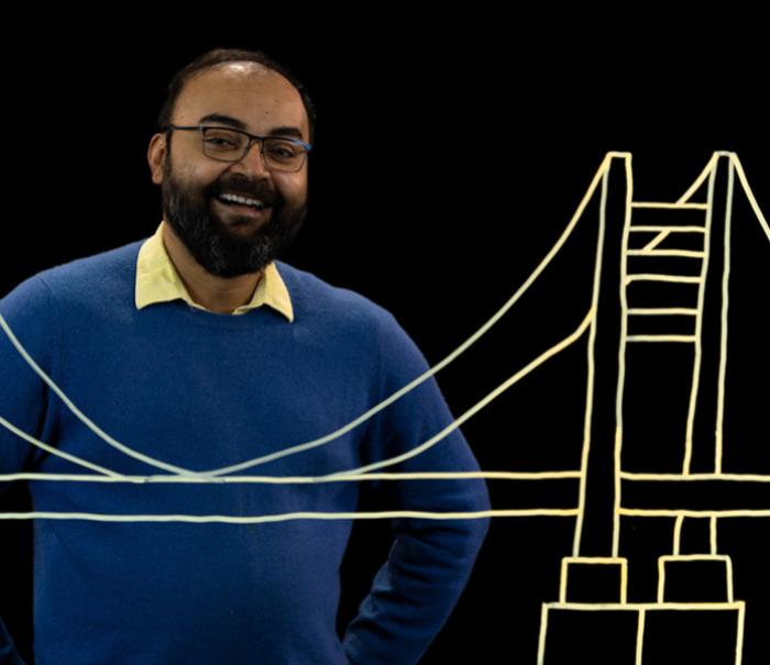 Sunasir Dutta stand behind an illustration of a bridge