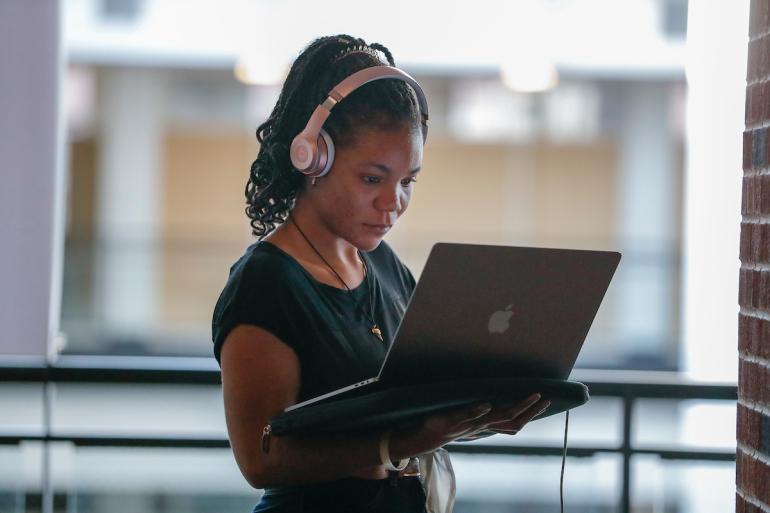 Student wearing headphones and holding laptop