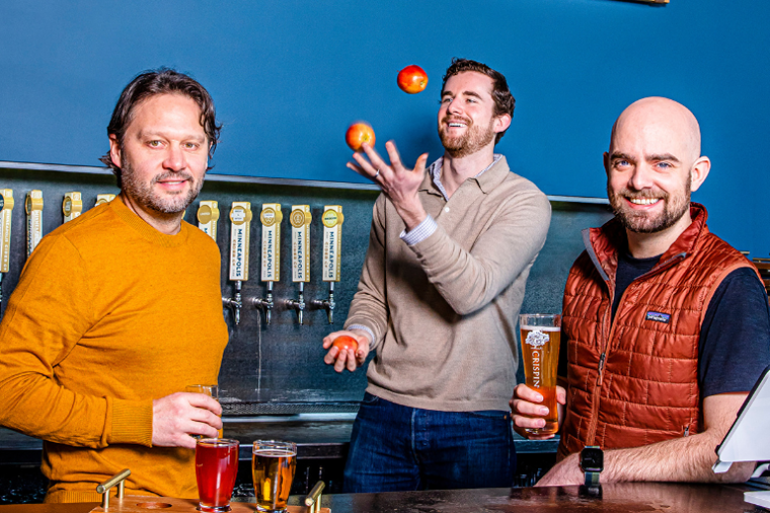 Minneapolis Cider Company's Rob Fisk, David O'Neill, and Jason Dayton with ciders behind the checkout counter at their brewery.