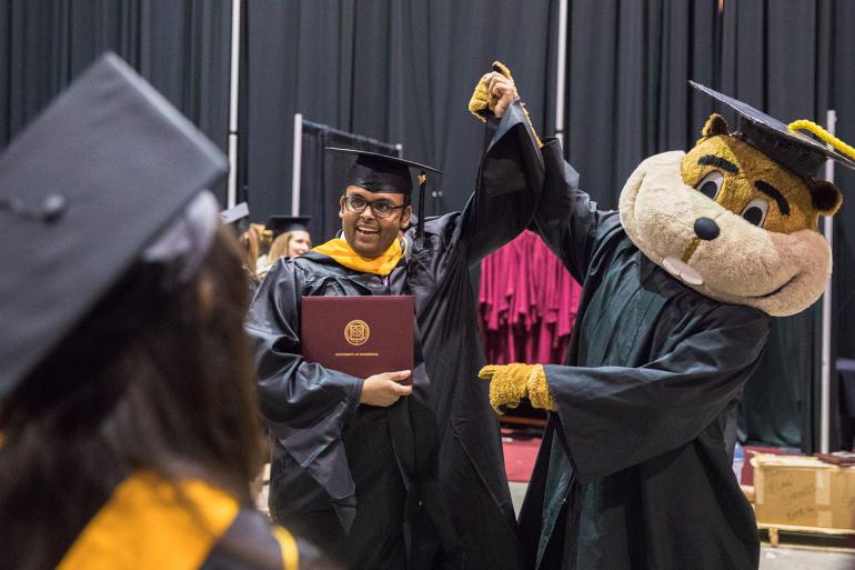 Goldy and new graduate celebrating at commencement