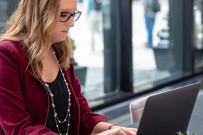 woman at desk typing on laptop