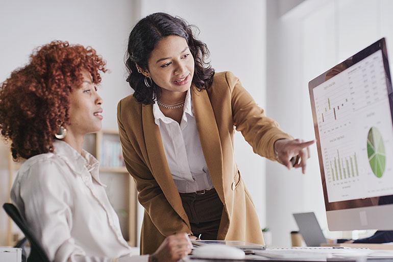 Woman pointing at charts on computer screen