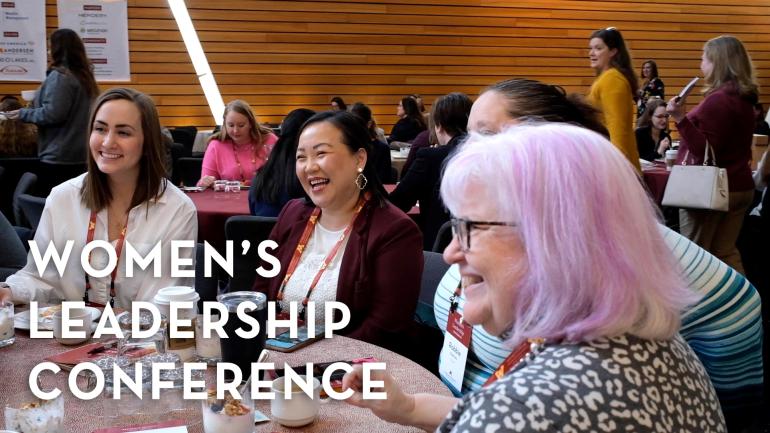 Women smile at a table while attending the Women's Leadership Conference.