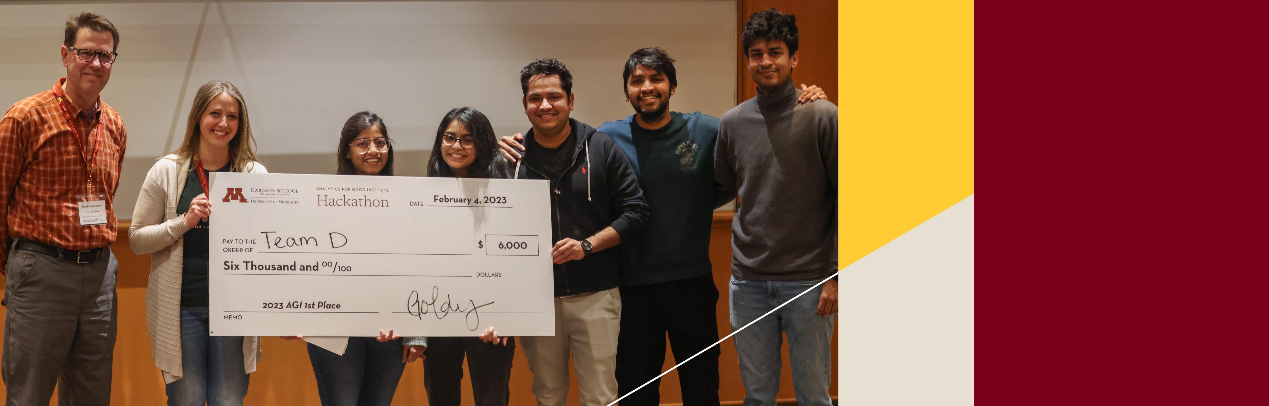 Hackathon winners pose with a giant check