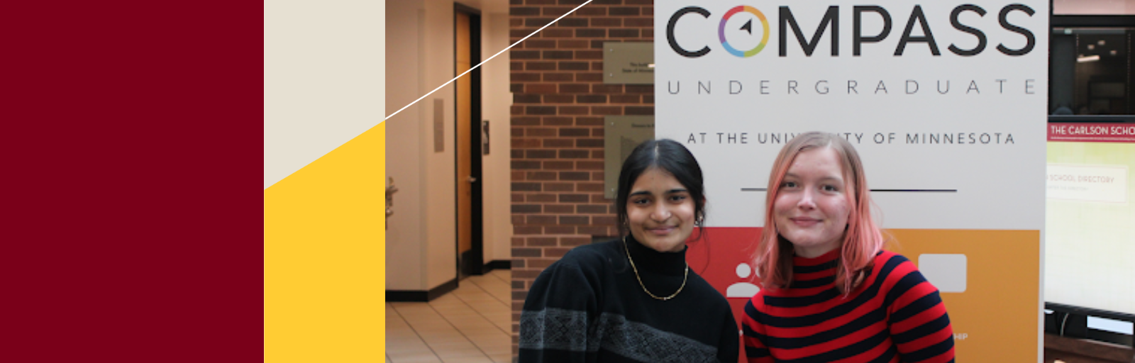 Two students sit in front of a sign promoting the Compass student organization.