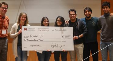 Hackathon winners pose with a giant check