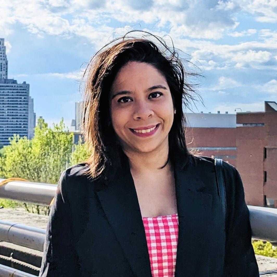 Abheesha Gautam posing in front of Minneapolis skyline on a windy day.