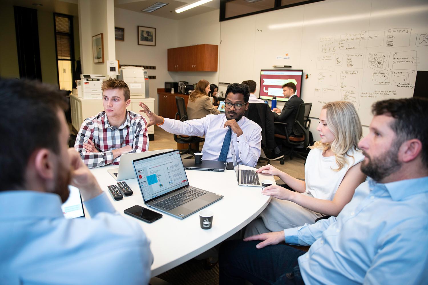 A diverse group of professionals engaged in a meeting around a round table in an office setting. 