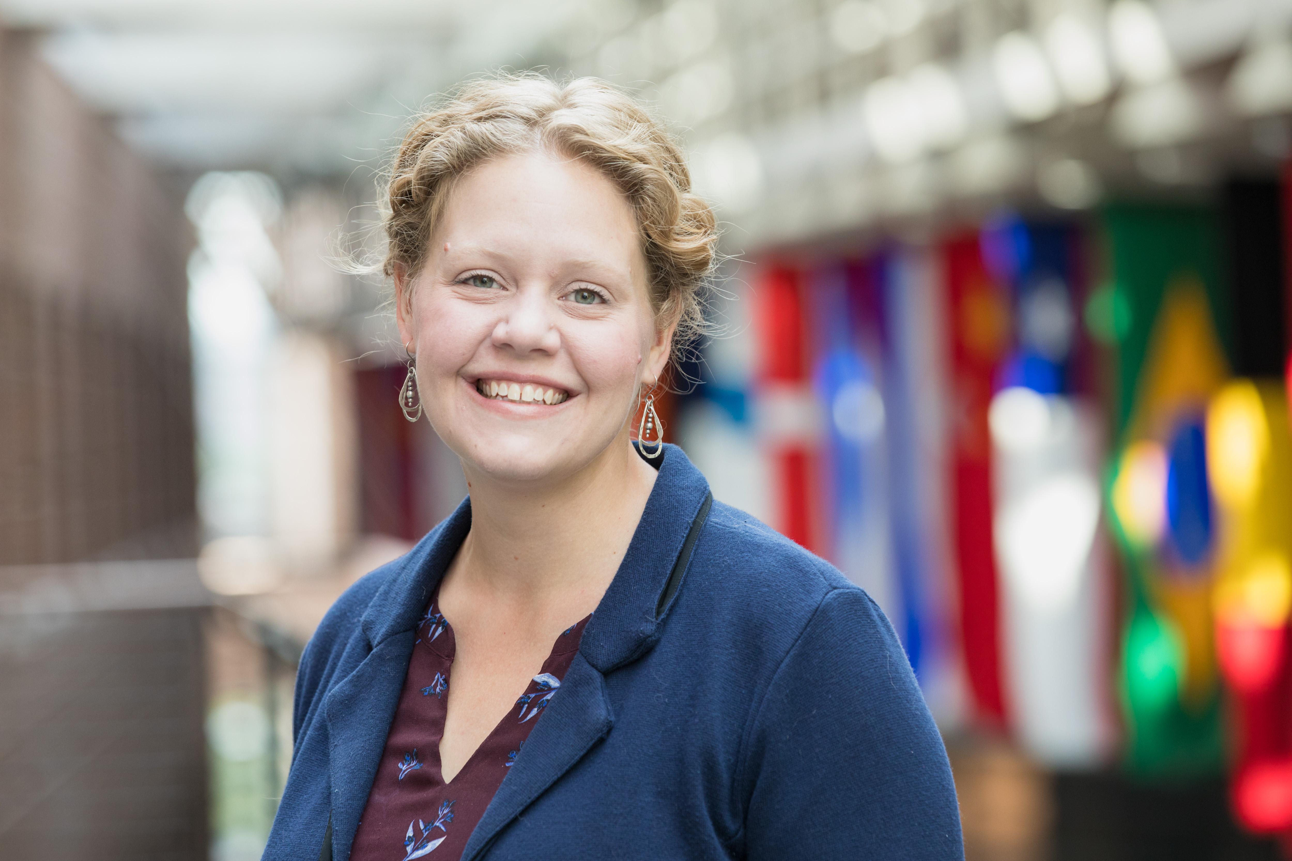 Headshot of Lauren Dickinson in front of international flags hanging in the Carlson School of Management building.