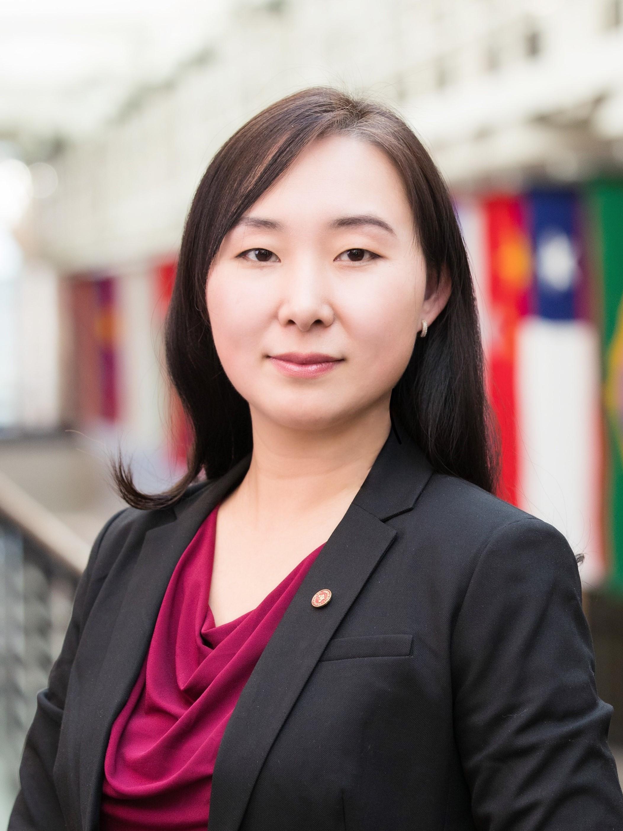 Headshot of Mandy Bai in front of international flags hanging in the Carlson School of Management building.