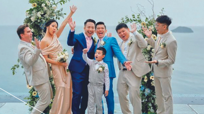 Alum Eric Lean and Matthew Aoyama posing with wedding party by the ocean.