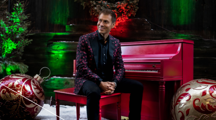 Musician Phil Thompson sitting at a piano with holiday decor around him