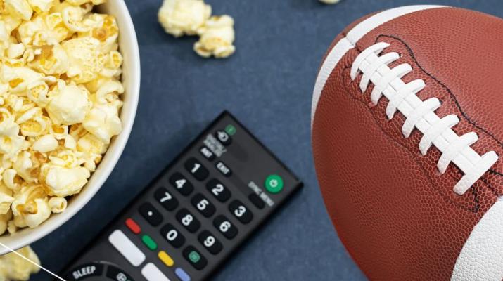 A graphic illustration of a football next to a TV remote and a bowl of popcorn