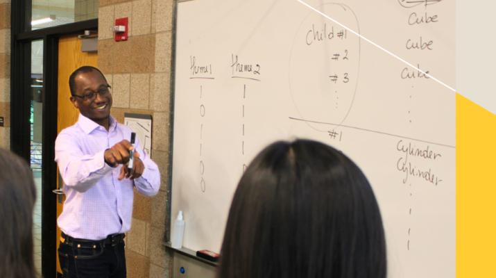 Professor Ibrahim Keita points at a student, smiling.