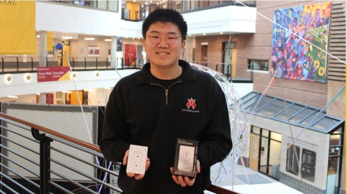 Leon Xue poses with an InvisOutlet and packaging in the Carlson School atrium.