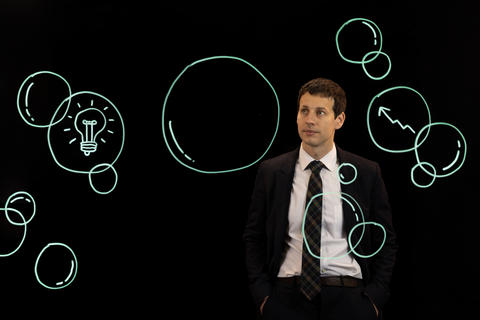 Erik Loualiche stands behind an illustration of bubbles