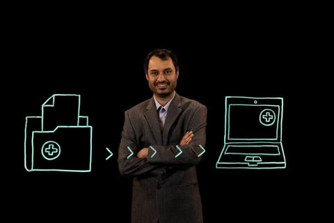 Kartik Ganju stands behind an illustrations of documents being transferred to a computer