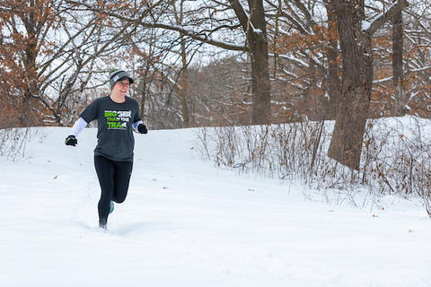 Mindy Bahr running down a snow covered trail during winter.