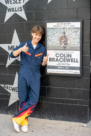 Colin Bracewell poses by a poster promoting his concert at 7th Street Entry in Minneapolis.