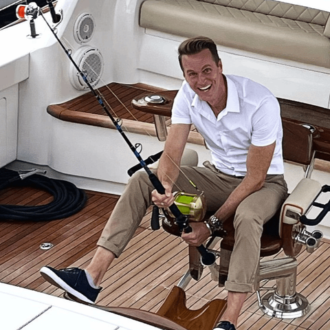 Chris Carlisle sitting on yacht with fishing rod