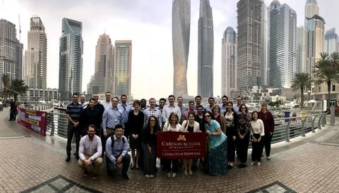 Group Posed with Carlson Flag in Front of Dubai Skyline