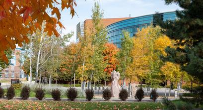 Image of the Carlson School of Management building through tress full of colorful fall leaves.