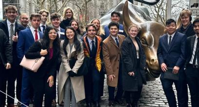 Students gather around the iconic bull statue on Wall Street.