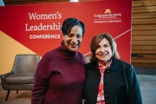 Nicole Graves and Beth Kieffer Leonard pose in front of Women's Leadership Conference poster.