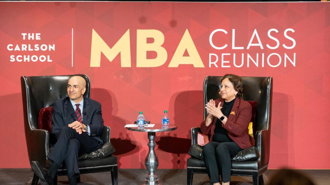 Dean Sri Zaheer and guest speaker Neel Kashkari sitting in front of a large "MBA Class Reunion" sign.