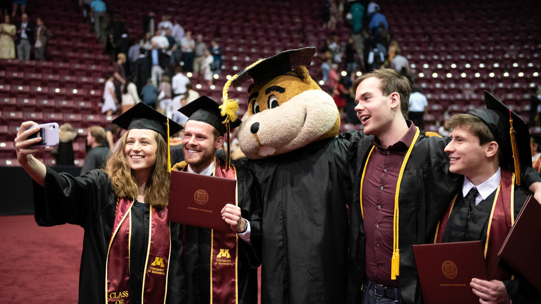 Undergraduate students posing for a photo with Goldy at the 2022 commencement ceremony