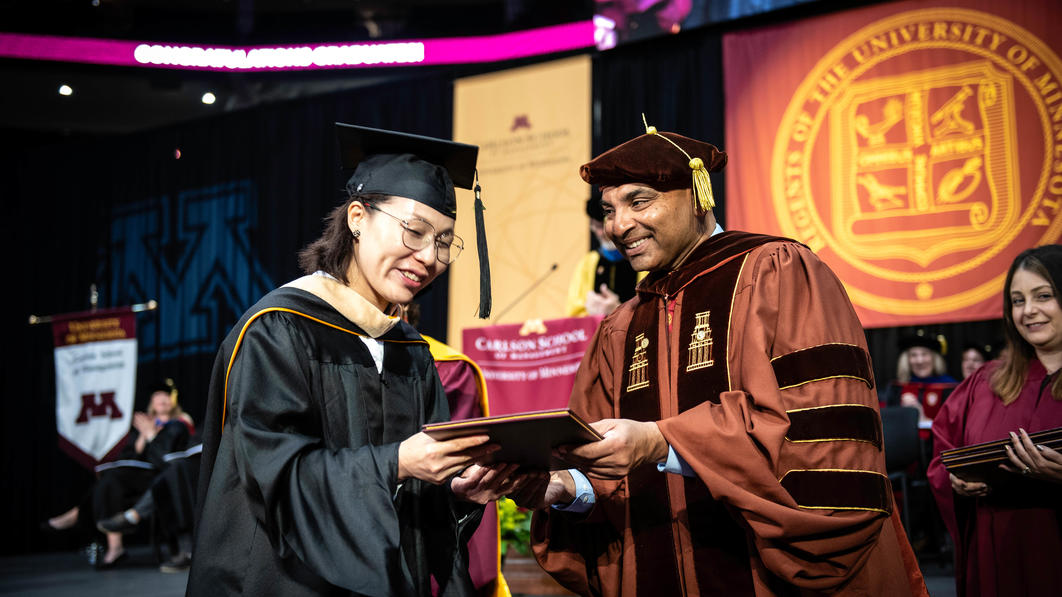 A graduate student from the CHEMBA program receives her diploma from Alok Gupta at the 2022 commencement ceremony